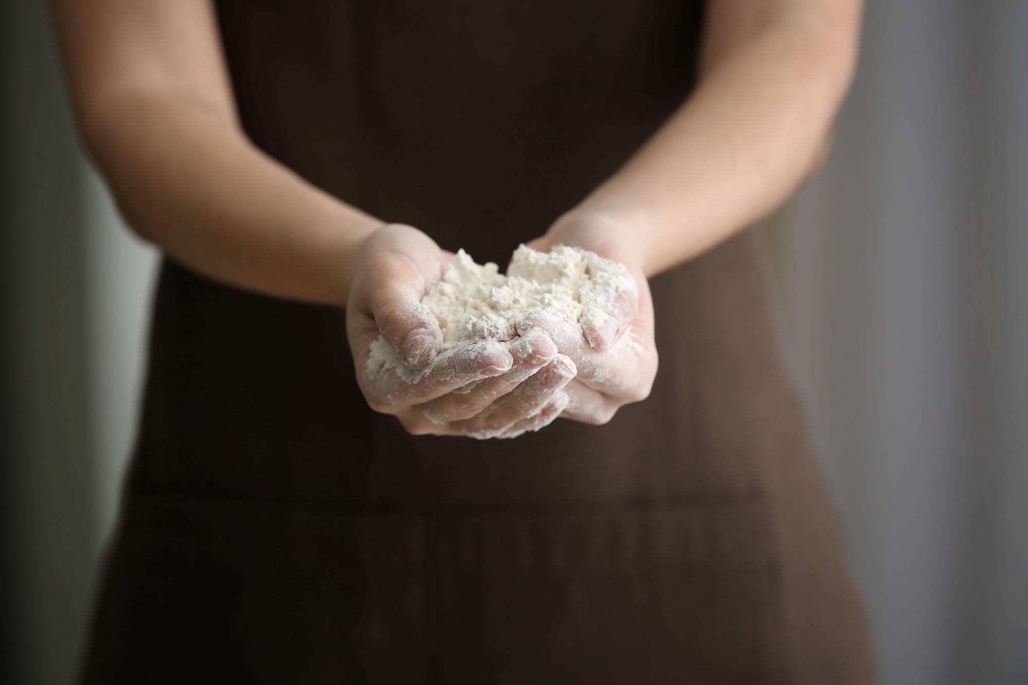 Close-up of hands kneading dough on floured board