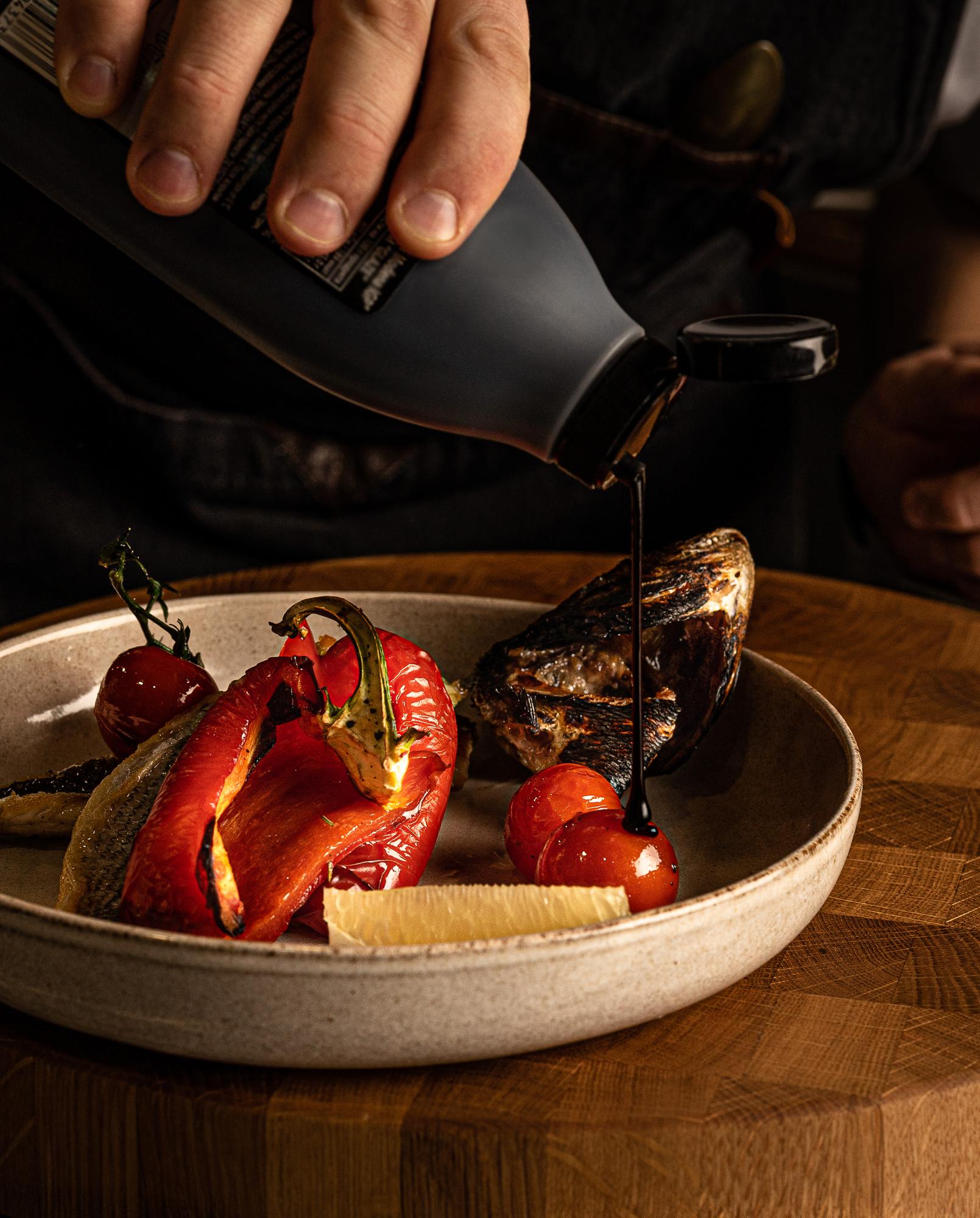 Chef arranging plated seasonal dish on wooden table